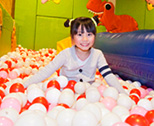 ボールがいっぱいのプールで遊ぶ笑顔の女の子
